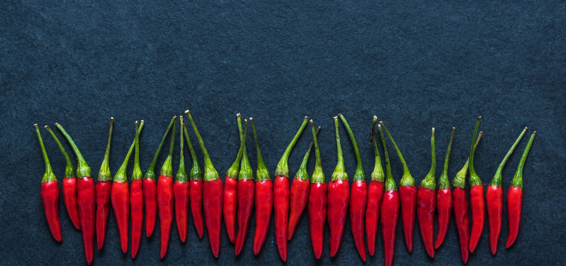 Red chilli hot peppers on black slate, food background